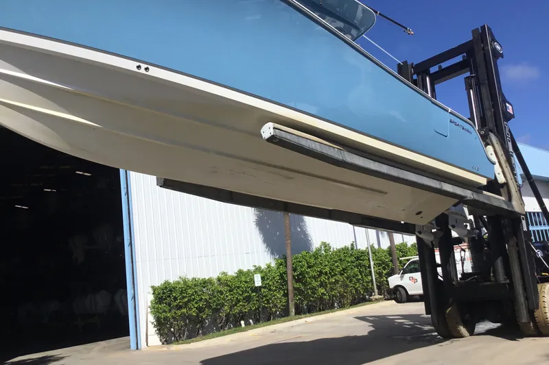 Slide: The Image of 2025 Sportsman Open 322 Center Console boat lifted by forklift near warehouse. - 73