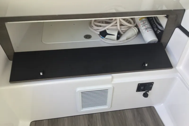 Slide: The Image of Storage compartment in 2025 Sportsman Open 322 Center Console boat with hose and fire extinguisher. - 31