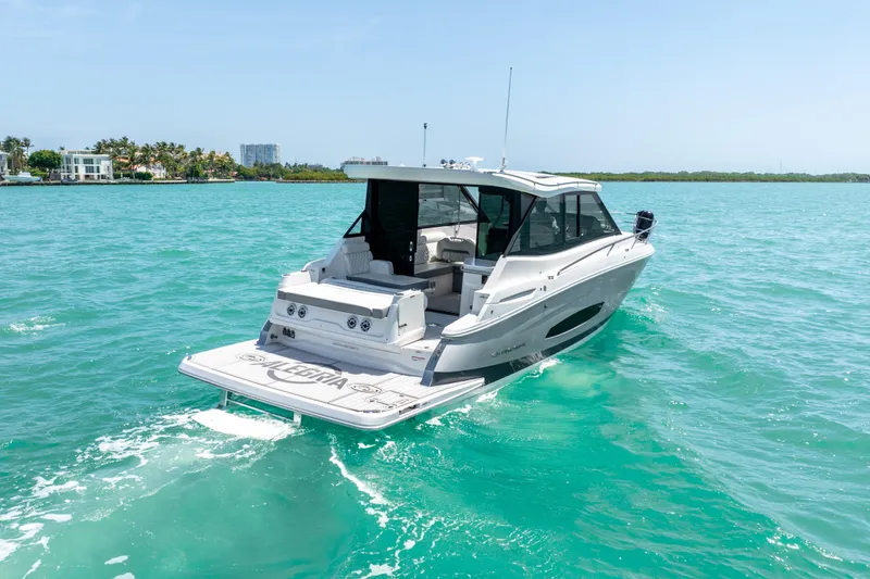 Slide: The Image of 2022 Regal 36 Grande Coupe cruising on turquoise waters near a tropical shoreline. - 6