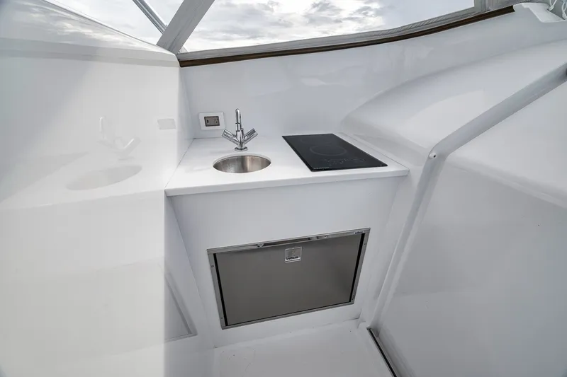 Slide: The Image of Compact galley area on 2025 Release Boatworks 46 Express, featuring sink, cooktop, and storage. - 60