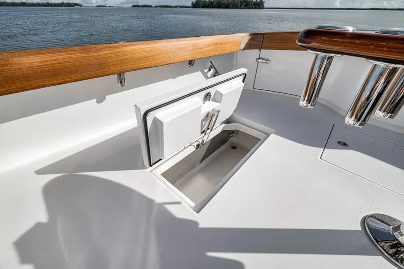 Slide: The Image of 2025 Release Boatworks 46 Express deck with open storage compartment, wooden rail, and rod holders. - 54