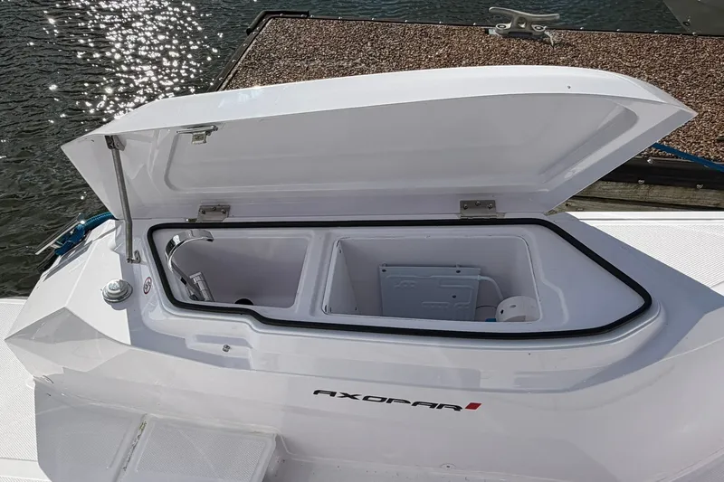 Slide: The Image of Open storage compartment on 2025 Axopar 29 XC Cross Cabin boat by the water. - 3