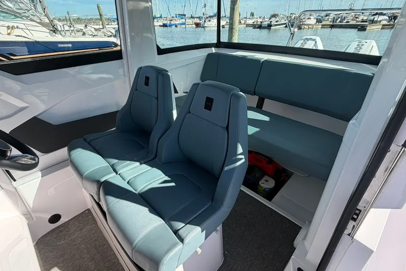 Slide: The Image of 2025 Axopar 29 XC Cross Cabin interior with blue seating and marina view. - 12