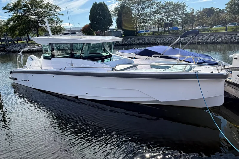 Slide: The Image of 2025 Axopar 29 XC Cross Cabin boat docked in a marina under clear skies. - 1