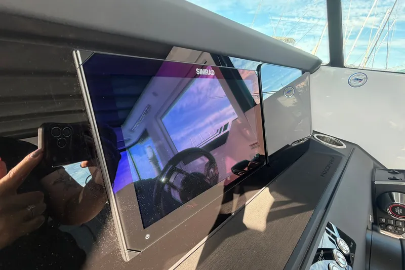 Slide: The Image of 2025 Axopar 29 XC Cross Cabin dashboard with Simrad display and steering wheel reflection. - 16
