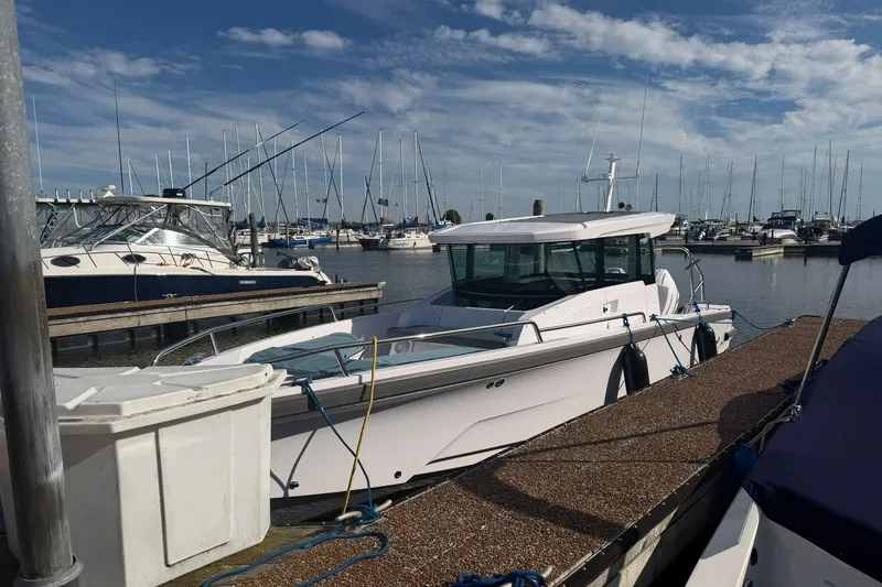 Slide: The Image of 2025 Axopar 29 XC Cross Cabin docked at a marina with sailboats in the background. - 2
