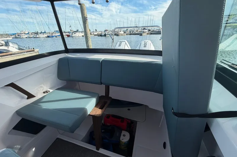 Slide: The Image of 2025 Axopar 29 XC Cross Cabin interior with marina view, featuring blue seating and storage. - 24