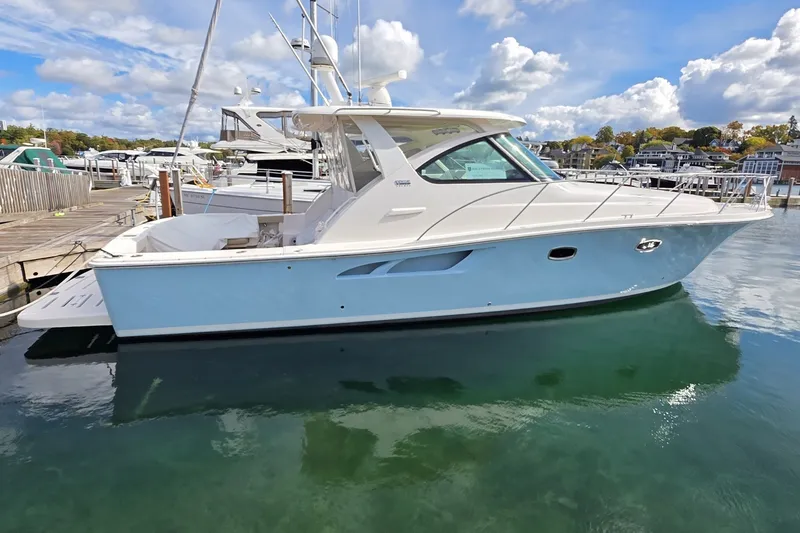 The Image of 2016 Tiara Yachts 3900 Coronet docked in a marina under a partly cloudy sky. - 0