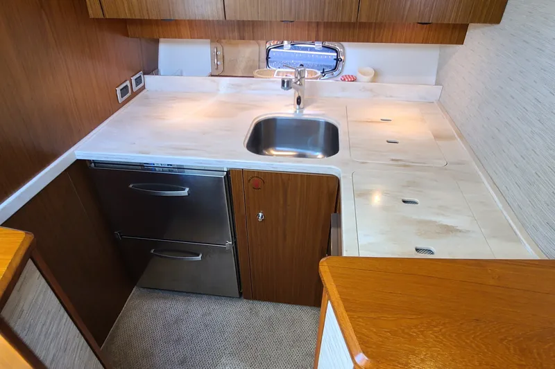 Slide: The Image of 2016 Tiara Yachts 3900 Coronet galley with stainless steel sink and wooden cabinetry. - 21