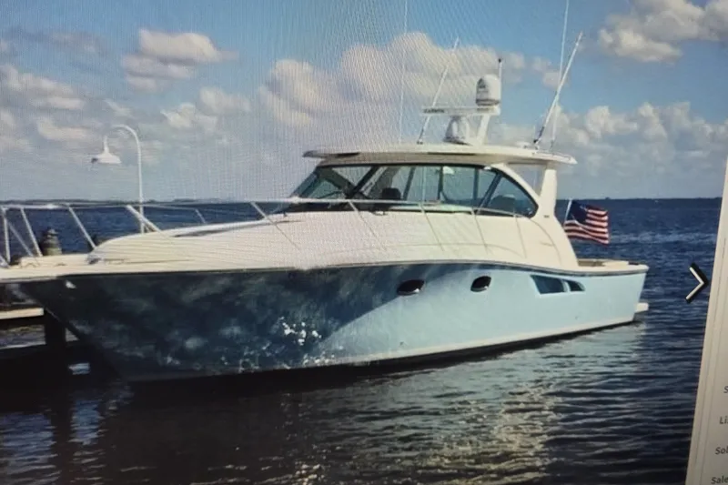 Slide: The Image of 2016 Tiara Yachts 3900 Coronet docked, featuring sleek design and American flag. - 1