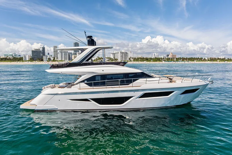 The Image of 2025 Ferretti Yachts 580 cruising near a coastal city skyline under a clear blue sky. - 1