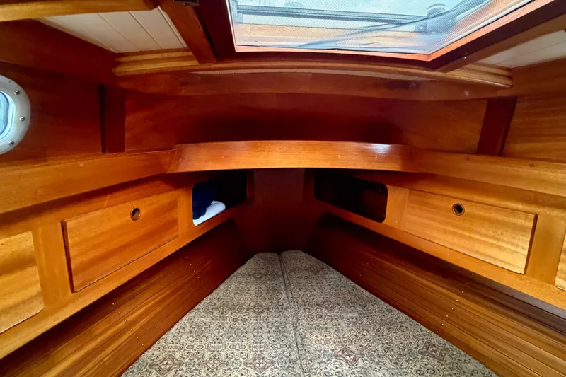 Slide: The Image of Interior of a 1987 Vindo 45 sailboat with wooden cabinetry and patterned bedding. - 46