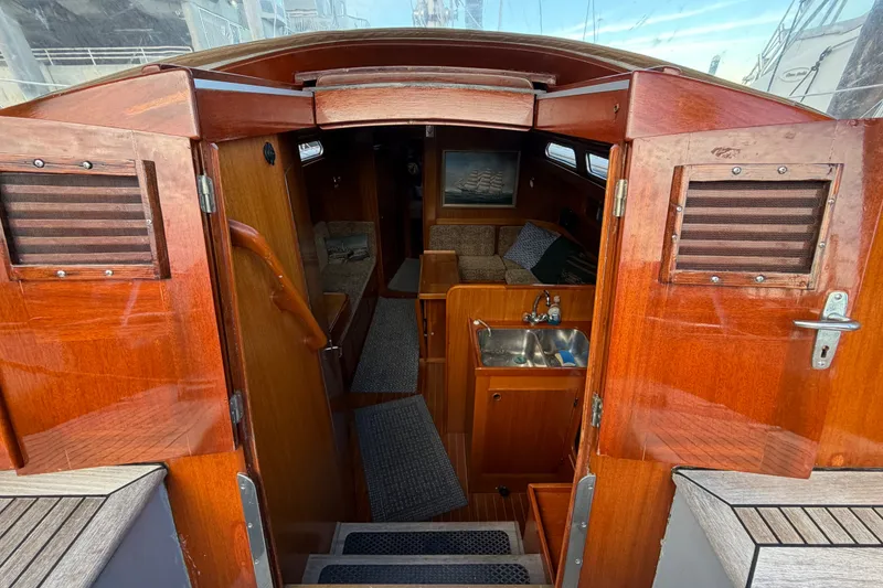 Slide: The Image of Interior view of a 1987 Vindo 45 sailboat, featuring wooden finishes and a compact kitchen area. - 27