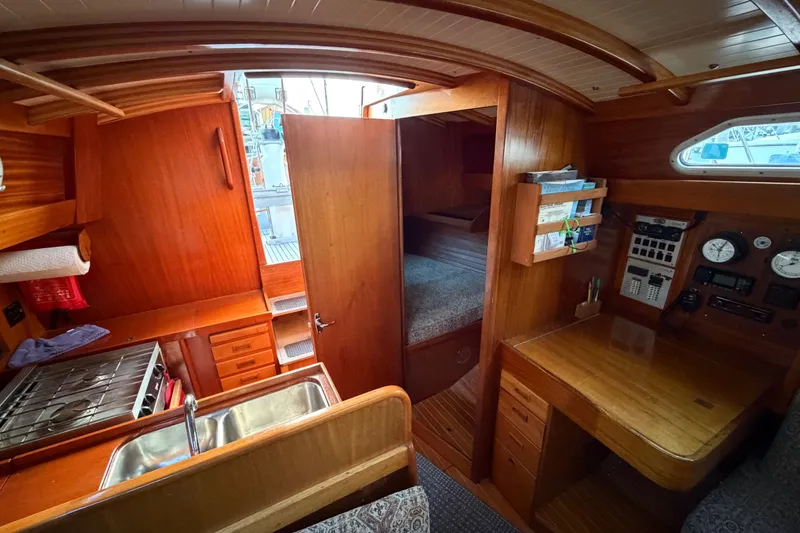 Slide: The Image of Interior of 1987 Vindo 45 sailboat with wood finish, kitchen, and navigation area. - 31