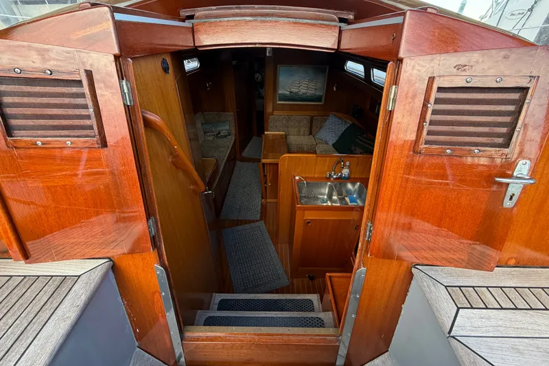 Slide: The Image of Interior view of a 1987 Vindo 45 sailboat, featuring wooden cabinetry and compact kitchen area. - 26
