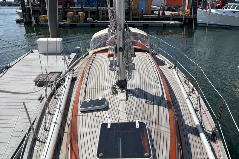 Slide: The Image of 1987 Vindo 45 sailboat docked, showcasing wooden deck and rigging in a marina setting. - 15
