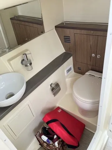 Slide: The Image of The image shows a modern boat bathroom with a sink, toilet, and storage space. - 15