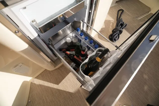 Slide: The Image of An open fridge on a boat with drinks, including water bottles and champagne. - 26