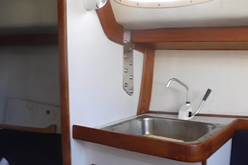 Slide: The Image of Interior of a 1997 Alerion Express 28 sailboat, featuring a compact sink and wooden trim. - 41