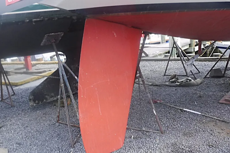 Slide: The Image of 1997 Alerion Express 28 sailboat keel on dry dock, supported by metal stands. - 8