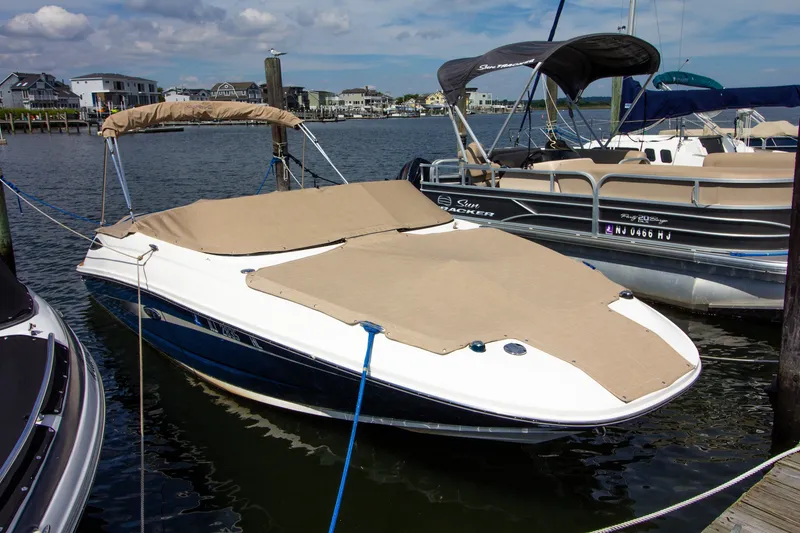Slide: The Image of A 2015 Sea Ray 220 Sundeck is docked, featuring covers over the deck. - 17