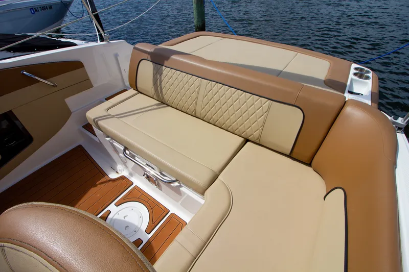 Slide: The Image of The 2015 Sea Ray 220 Sundeck features an elegant, cushioned bench seat with a quilted pattern. - 35
