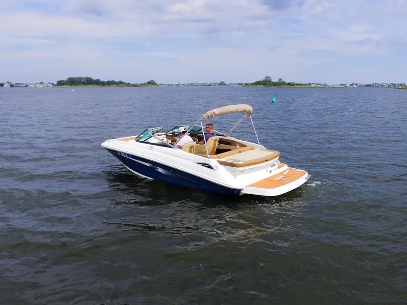 Slide: The Image of A 2015 Sea Ray 220 Sundeck on calm water with two people on board. - 10
