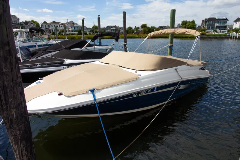Slide: The Image of A 2015 Sea Ray 220 Sundeck docked, featuring a beige cover. - 18