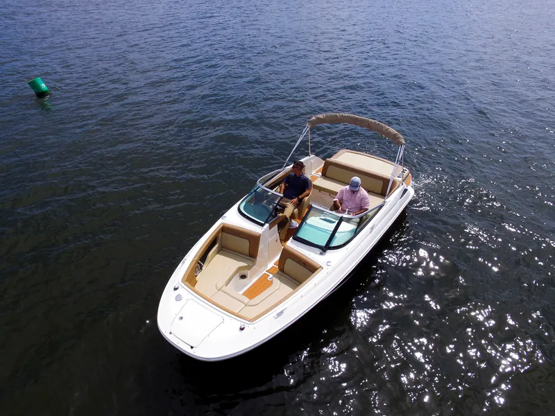 Slide: The Image of Two people sit in a Sea Ray 220 Sundeck boat on calm water. - 13