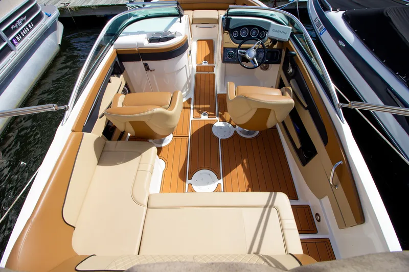 Slide: The Image of The image shows the cockpit of a 2015 Sea Ray 220 Sundeck with beige seats and wood flooring. - 32