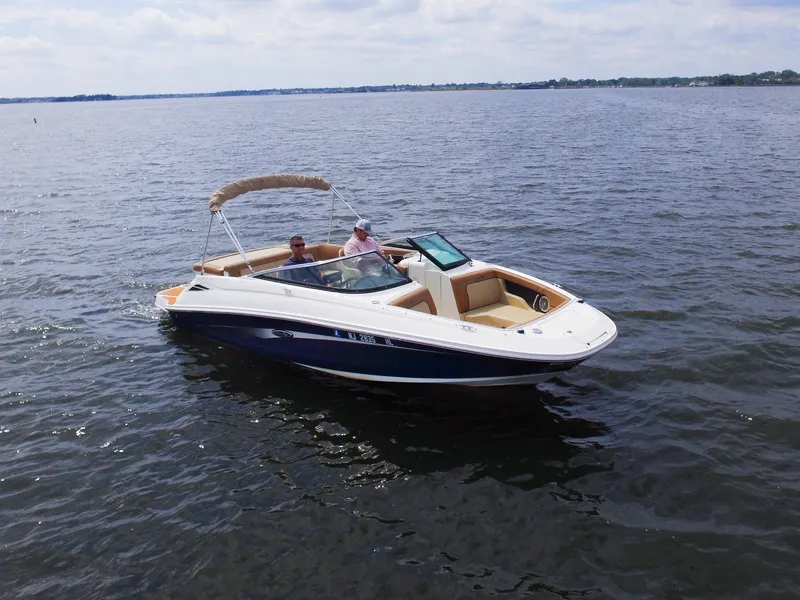 Slide: The Image of A 2015 Sea Ray 220 Sundeck on calm water with two people on board. - 6