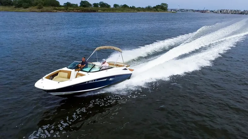 Slide: The Image of A 2015 Sea Ray 220 Sundeck speeds across the water with two people on board. - 3