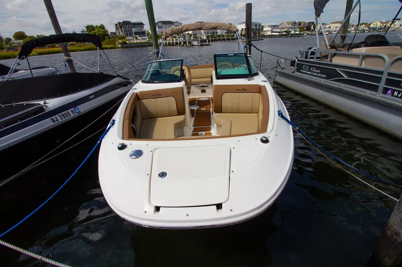 Slide: The Image of A 2015 Sea Ray 220 Sundeck docked. It features a white exterior and beige upholstery. - 21