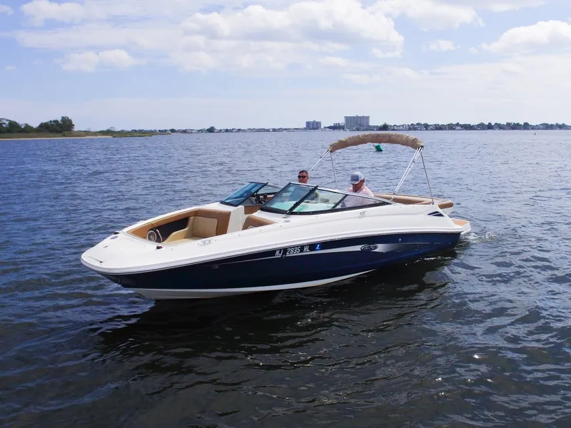 Slide: The Image of A 2015 Sea Ray 220 Sundeck on calm water with two people on board. - 8