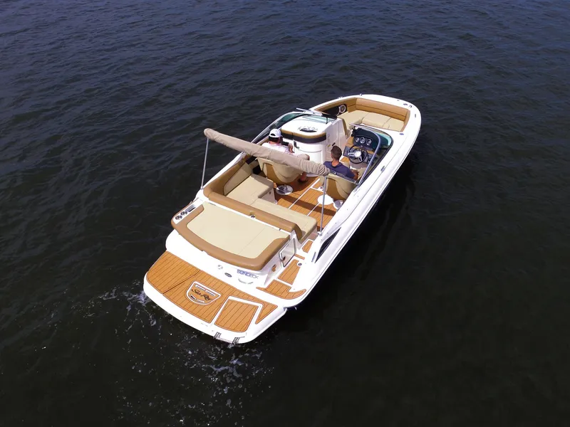 Slide: The Image of A 2015 Sea Ray 220 Sundeck on the water with a sunshade and beige interior. - 15