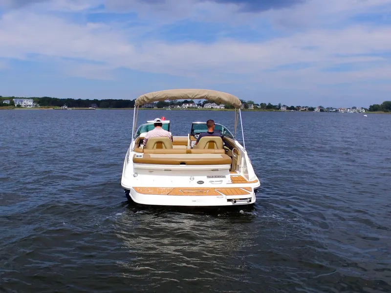 Slide: The Image of A 2015 Sea Ray 220 Sundeck on calm waters with two people on board. - 11