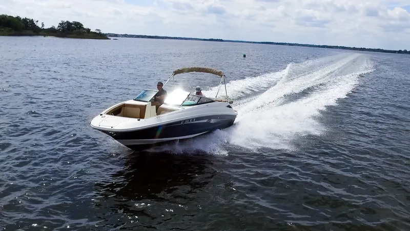 Slide: The Image of A 2015 Sea Ray 220 Sundeck speeds across the water with two people on board. - 2