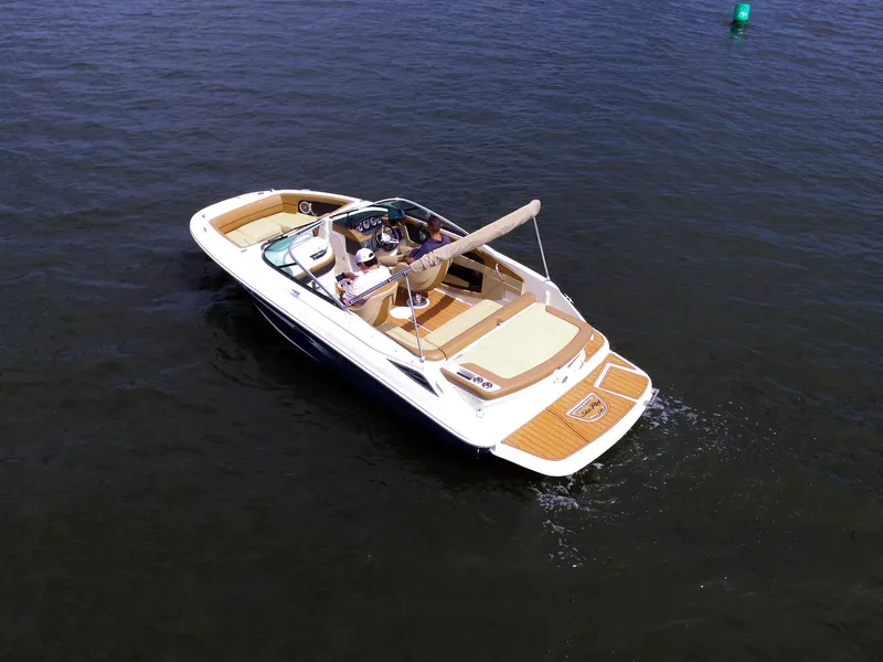 Slide: The Image of 2015 Sea Ray 220 Sundeck on calm water, with several people on board enjoying the sun. - 12