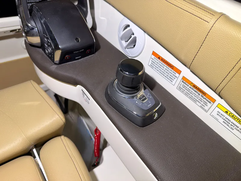 Slide: The Image of Close-up of a joystick control on a 2026 Sea Ray Sundancer 320 Outboard, surrounded by warning labels. - 23