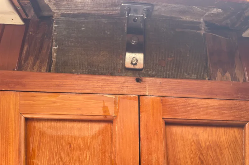 Slide: The Image of Wooden interior of 1986 Slocum 43 boat showing cabinet and metal bracket. - 43