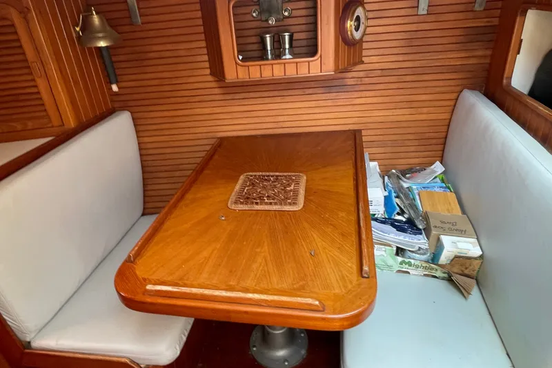Slide: The Image of Cozy 1986 Slocum 43 sailboat interior with wooden table and cushioned seating. - 34