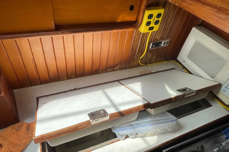 Slide: The Image of 1986 Slocum 43 yacht interior with wooden paneling, storage compartments, and electrical outlets. - 33