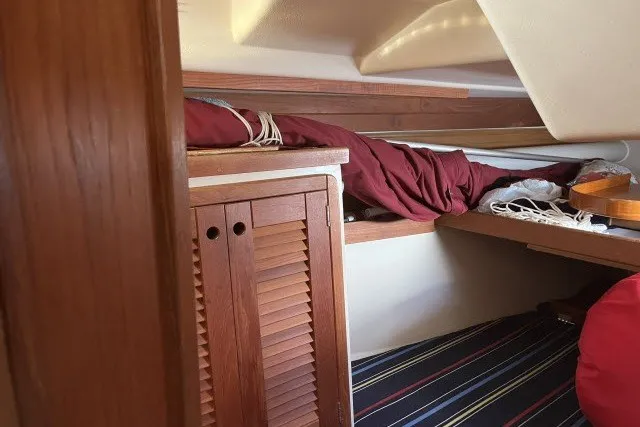 Slide: The Image of Interior cabin of a 1990 Catalina 42 sailboat with wooden cabinetry and striped bedding. - 17
