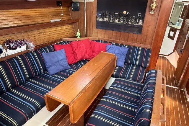 Slide: The Image of Cozy interior of 1990 Catalina 42 sailboat with striped seating and wooden table. - 3