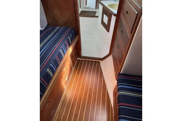 Slide: The Image of Interior of 1990 Catalina 42 sailboat with striped bedding and wooden flooring. - 12