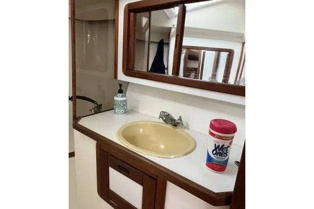 Slide: The Image of 1990 Catalina 42 yacht bathroom with sink, mirror, and cleaning supplies. - 14