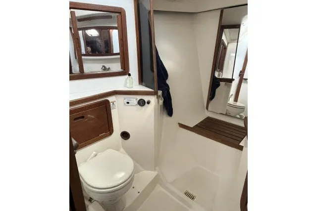 Slide: The Image of 1990 Catalina 42 yacht bathroom with toilet, wooden accents, and mirror. - 13