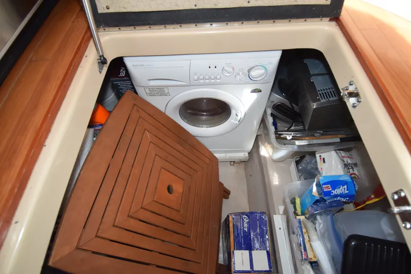 Slide: The Image of Laundry area with washing machine and storage on a 2005 Sea Ray 500 Sedan Bridge yacht. - 16