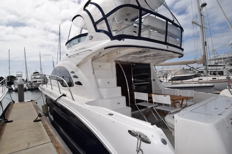 Slide: The Image of 2005 Sea Ray 500 Sedan Bridge yacht docked at marina, featuring spacious deck and seating area. - 34