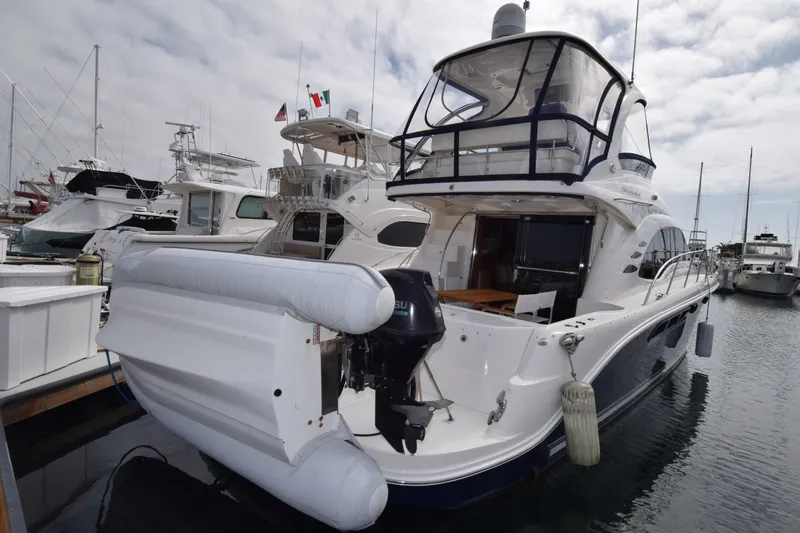 Slide: The Image of 2005 Sea Ray 500 Sedan Bridge yacht docked at marina, featuring spacious deck and inflatable boat. - 27